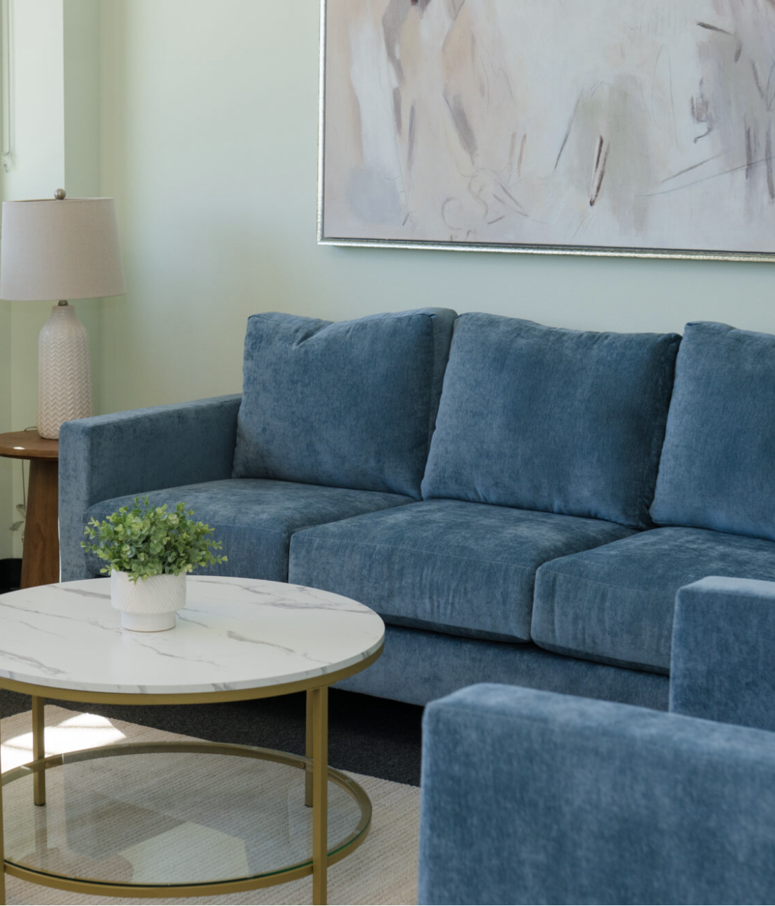 Therapy office with deep blue sofa, soft lamp light, and abstract artwork